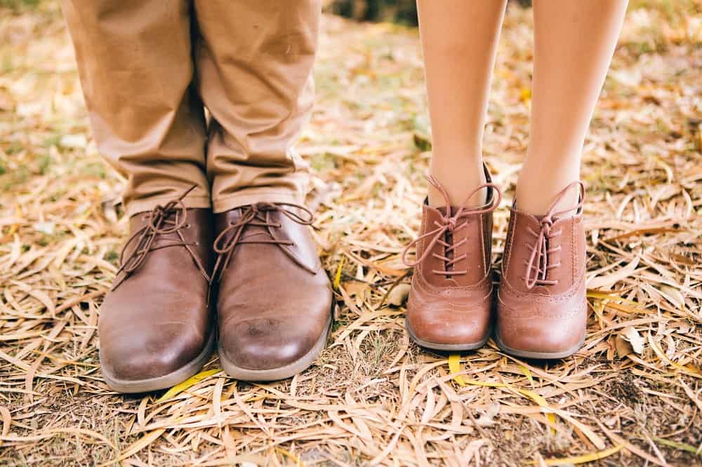 de benen van een man en vrouw met bruine leren schoenen aan in de herfst