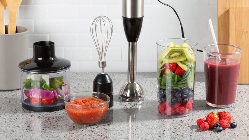 Blender met allerlei accessoires en groente eromheen op aanrecht