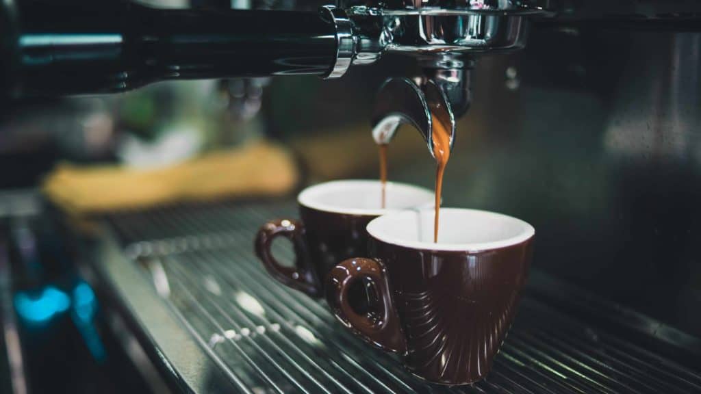 koffie drupt vanuit koffiemachine in twee kopjes