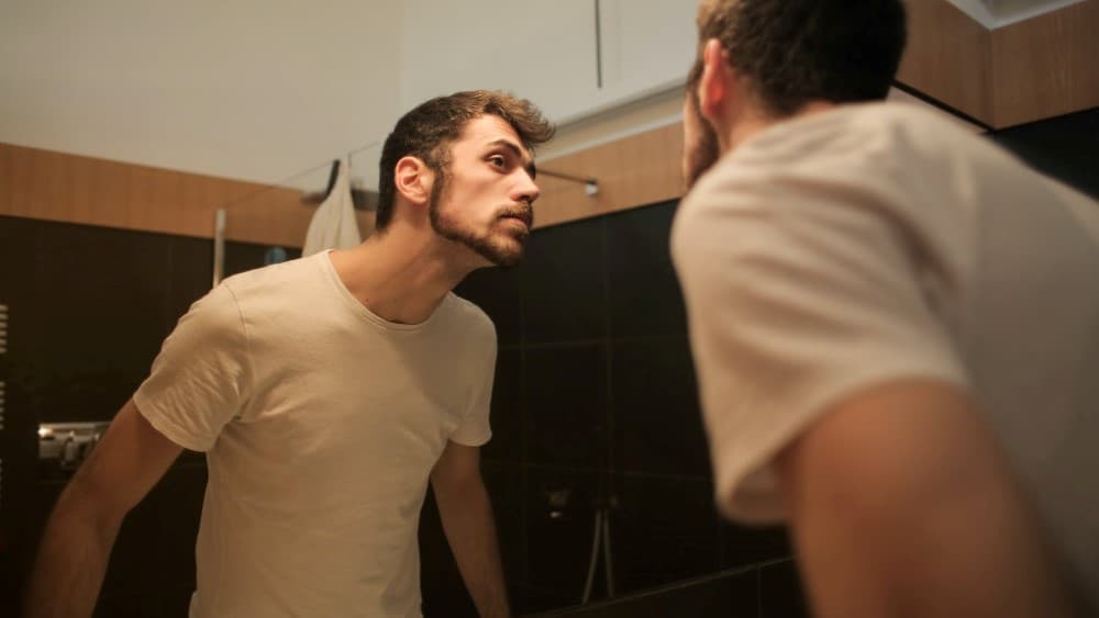 Man kijkt in spiegel naar baard