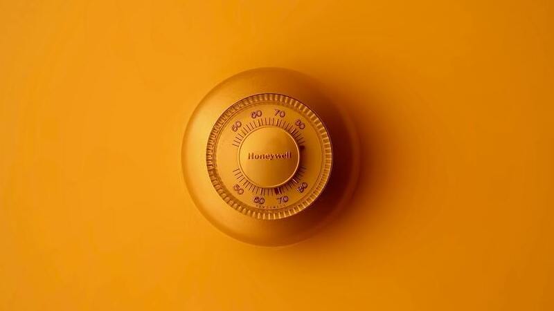 Thermostaat hangt aan gele muur