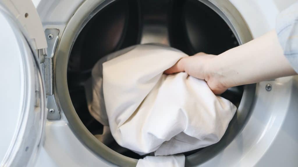 vrouw doet beddengoed in de droger