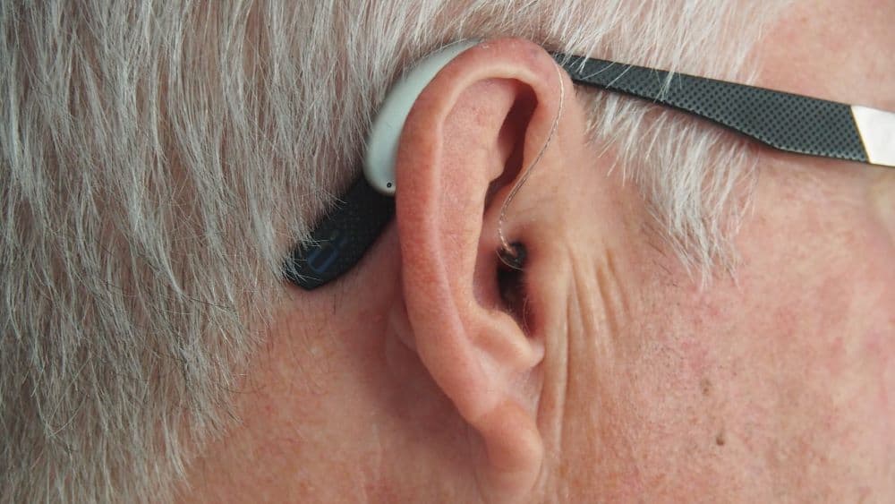 Iemand met gehoorapparaat in en rondom oor
