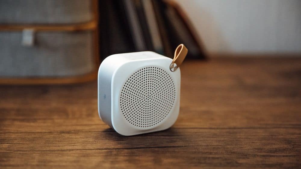 Kleine witte Bluetooth-speaker op een houten tafelblad