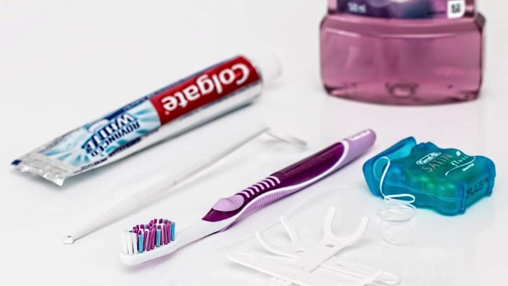 Tandenborstel naast tandpasta, flosdraad, stoker en mondwater