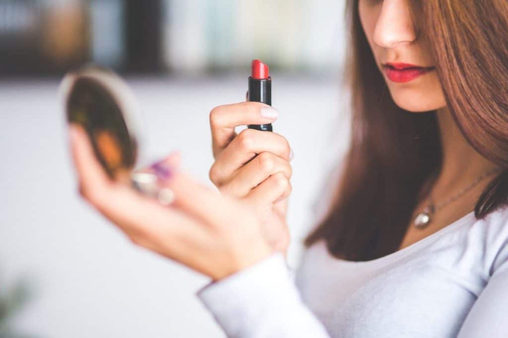 Vrouw brengt rode lippenstift aan