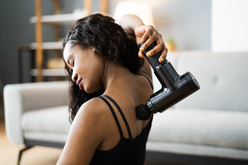 Vrouw met massage gun op rug