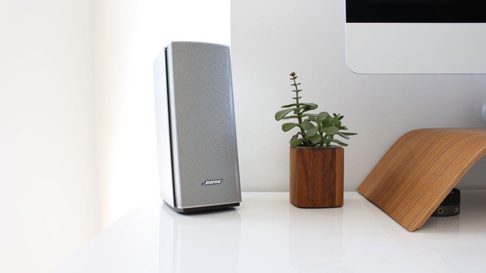 Zilveren bose pc-speaker naast een plantje en een imac