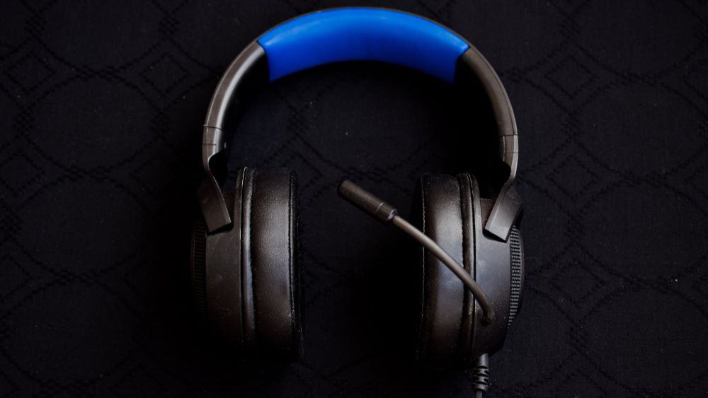 Zwarte gaming headset met blauw vlak op de hoofdband tegen zwarte achtergrond