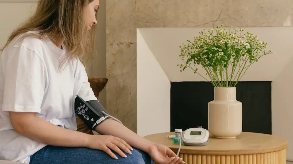 Vrouw in wit shirt gebruikt bovenarmbloeddrukmeter