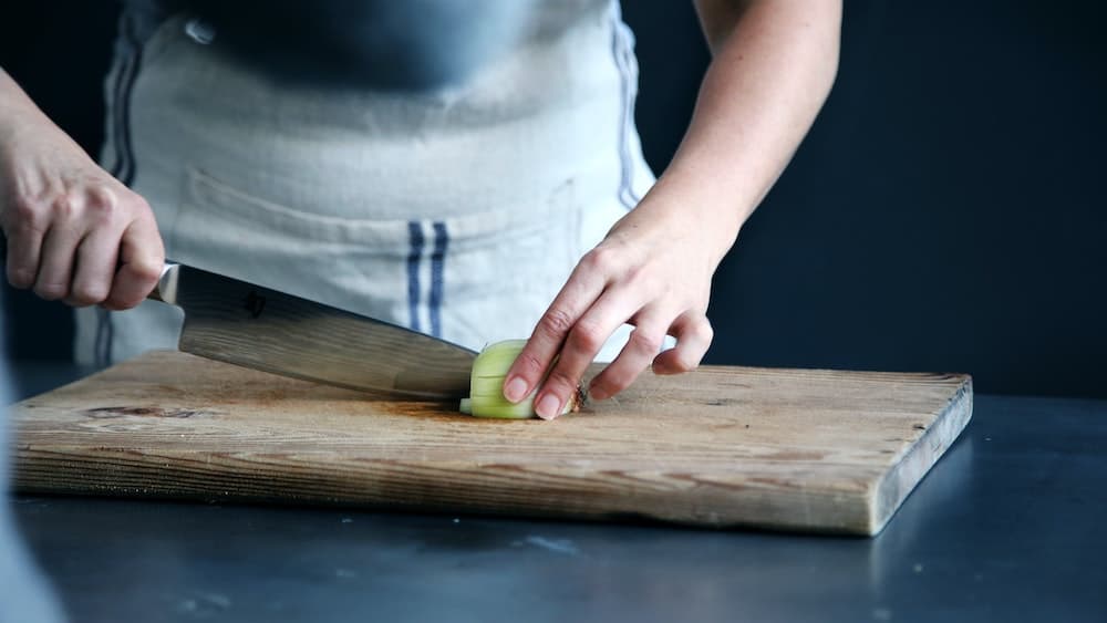 persoon snijdt ui met groot mes