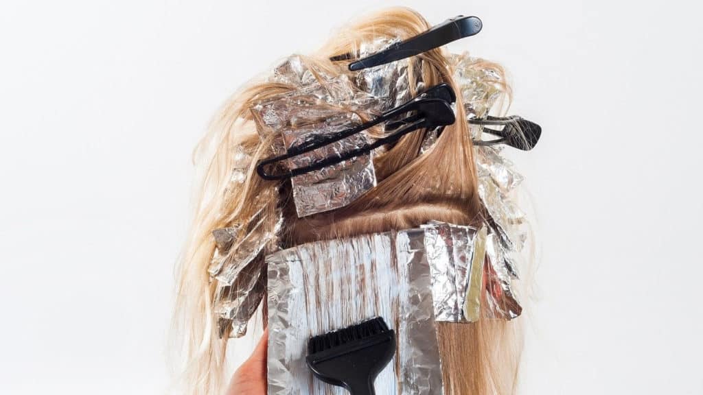 Hoofd van achteren met blond haar waarin folie en clips zitten