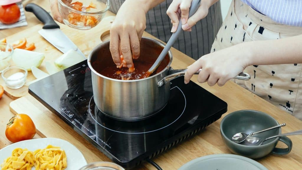 Inductiekookplaat met daarop een pan waar een gerecht in wordt bereid.