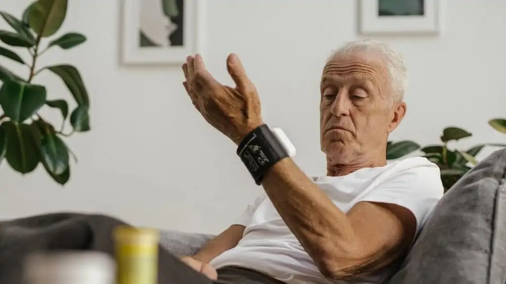 Man met grijs haar gebruikt polsmeter