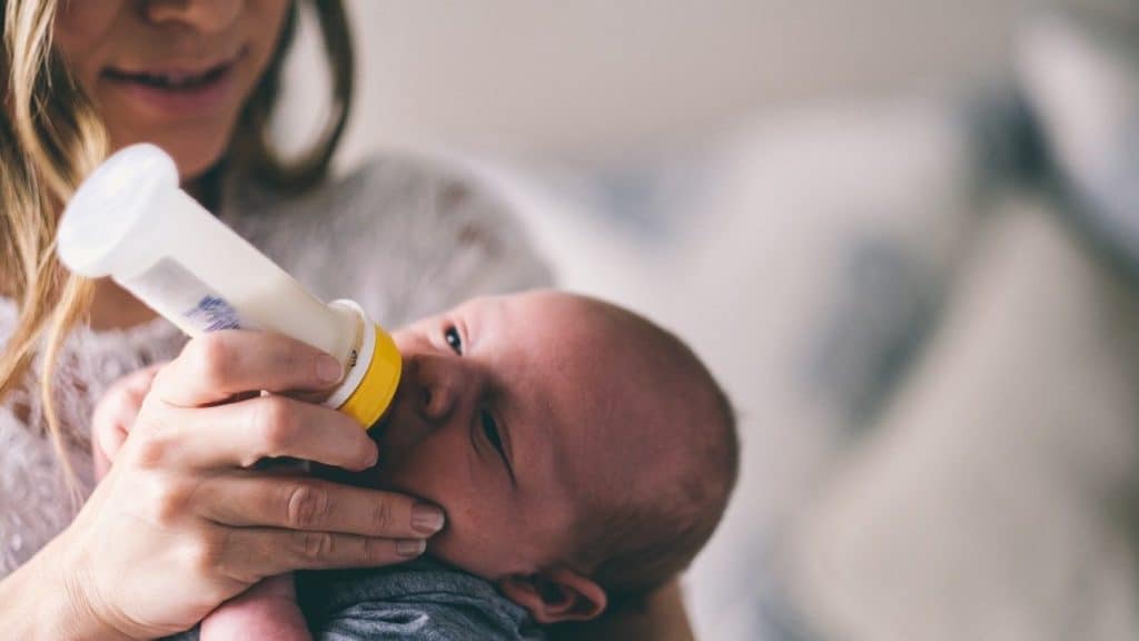 baby wordt op de arm gevoed door fles