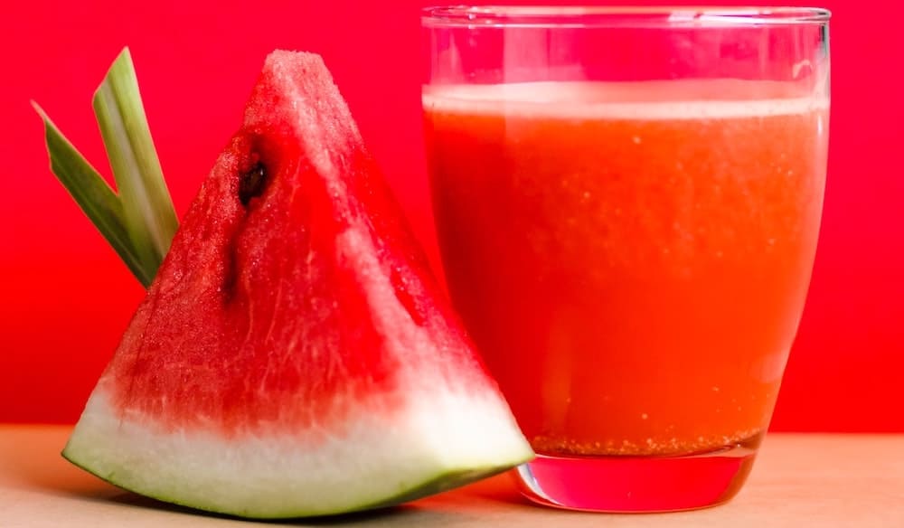 rood sapje in glas naast watermeloen