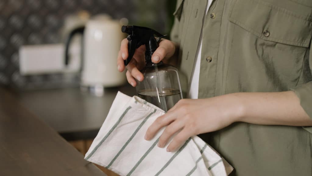 handen houden theedoek en sprayer vast in keuken