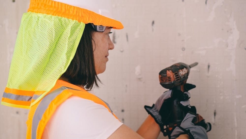 Een vrouw boort een gat in een betonnen muur met een boorhamer.
