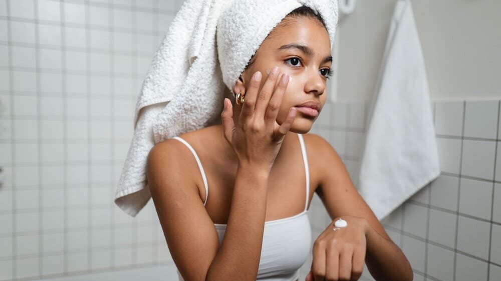 Vrouw die crème aanbrengt op haar gezicht.
