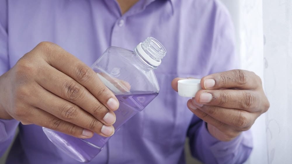 handen gieten mondwater in een dopje