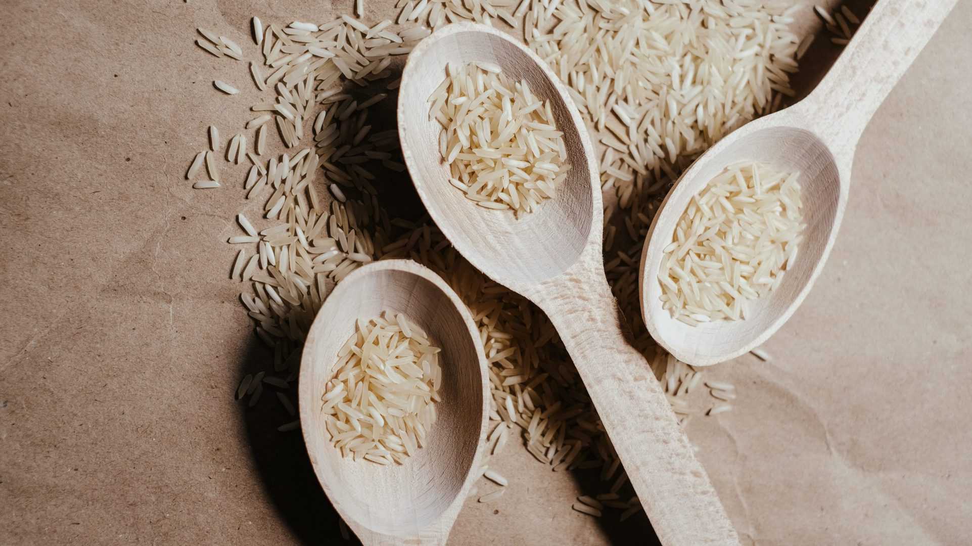 rijst op houten lepels op bruine ondergrond