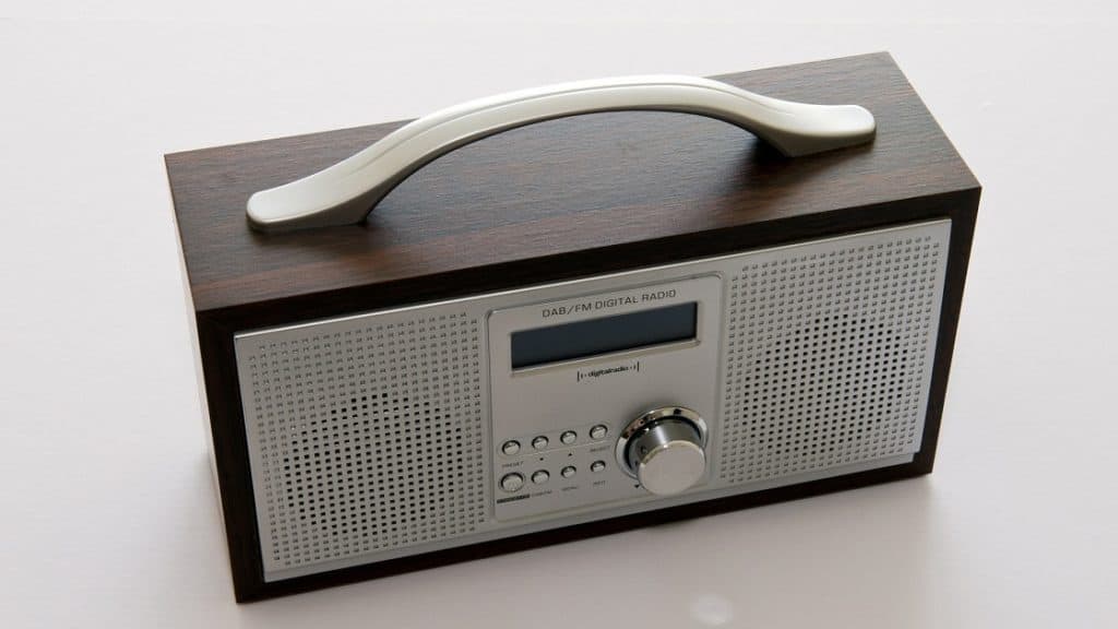 Houten draagbare DAB+ radio met witte voorkant en aan de bovenkant een handvat.