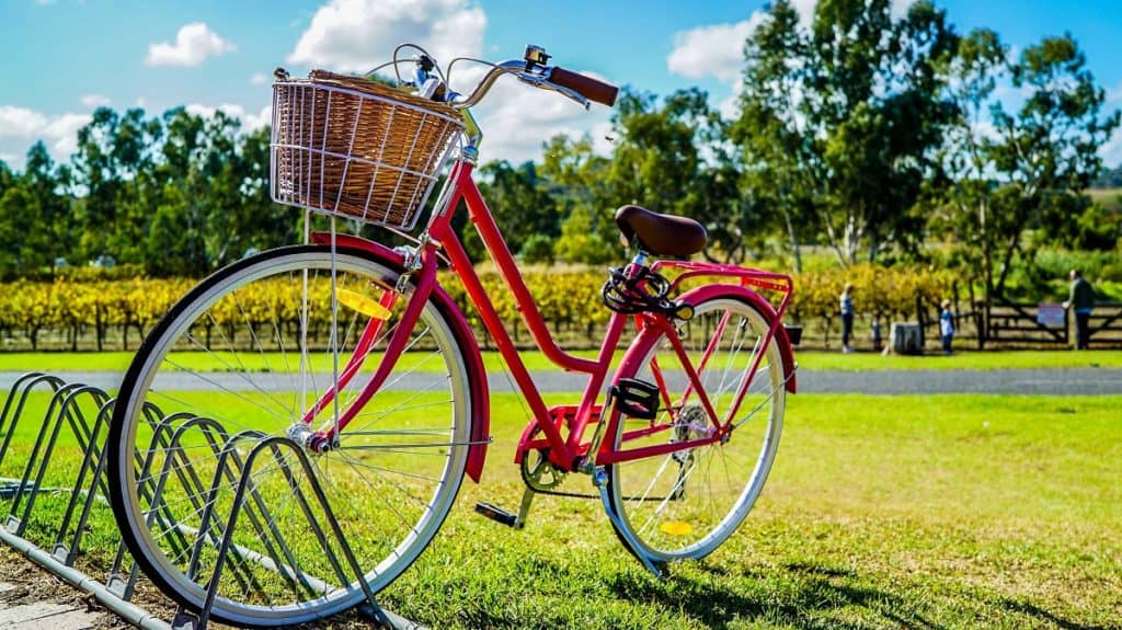 Rode transportfiets met een mandje voorop en een bagagedrager.