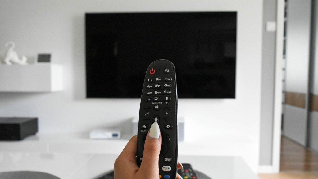 afstandsbediening wordt gericht naar tv scherm in woonkamer