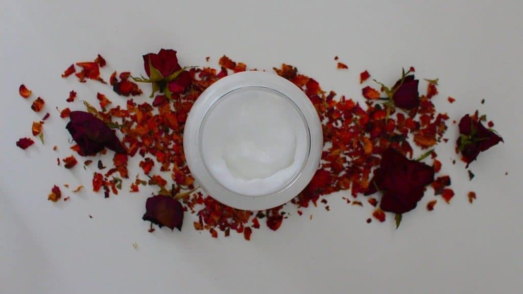 pot witte creme op witte tafel omringd door bloemblaadjes