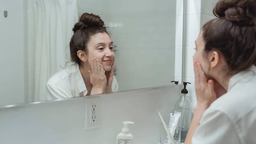 Vrouw doet crème op in de spiegel