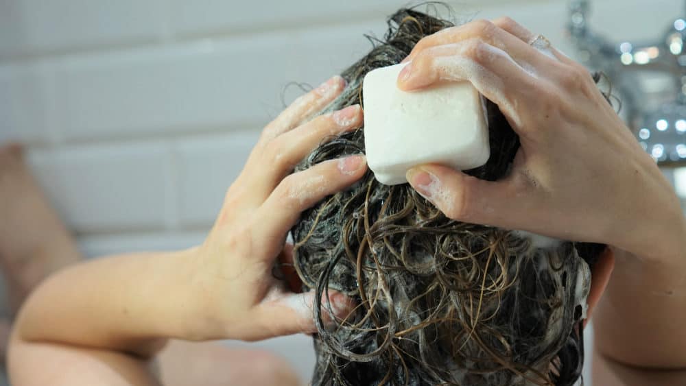 Vrouw die haar haren wast met een shampoo bar