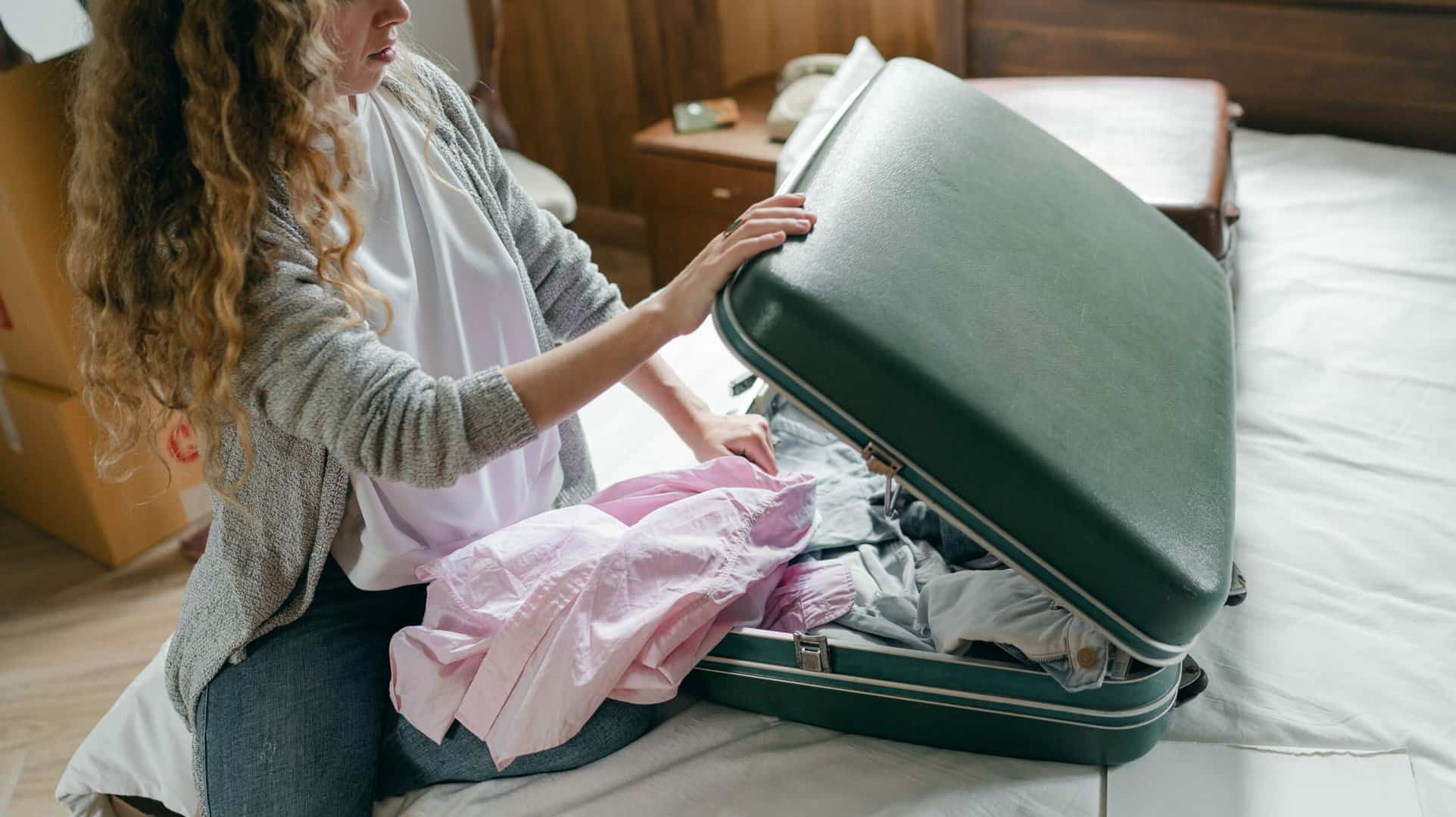 Vrouw pakt groene hardcase koffer met kliksluiting in