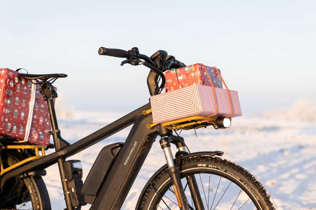 Elektrische fiets met cadeaus op winters landschap tijdens zonsopgang