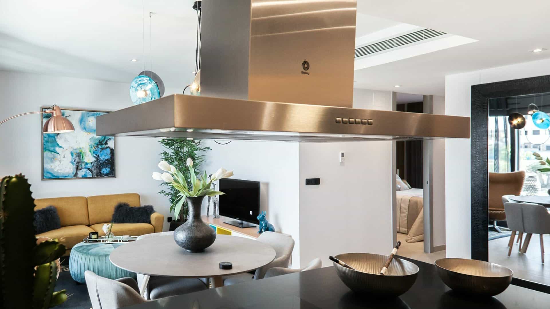 Zilveren afzuigkap boven een kookplaat, in een open keuken.